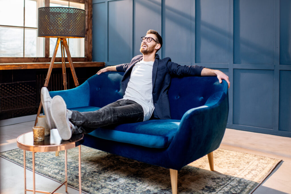 Portrait of relaxed businessman dressed casualy sitting on the couch at the luxury office with blue walls