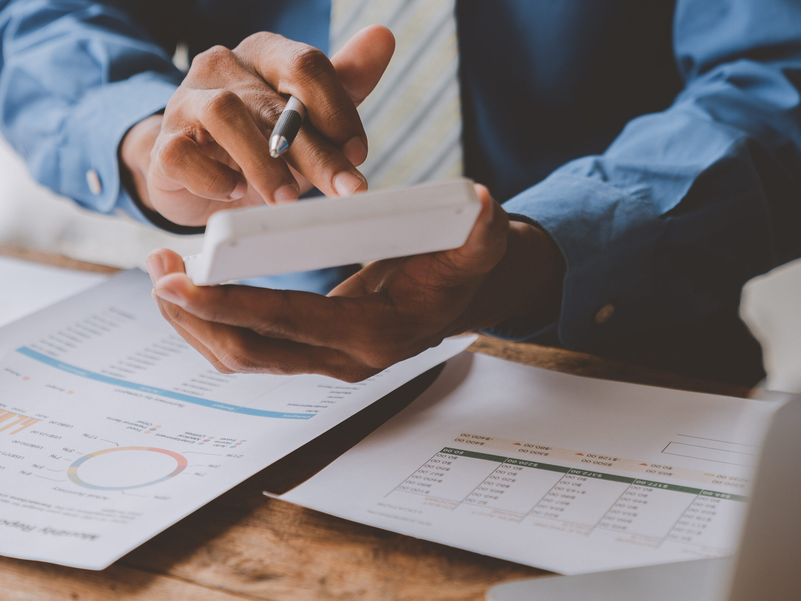 Businessman, investor analyzing financial report situation with calculator to calculate investment and accounting in real estate project at desk showing business growth in office.