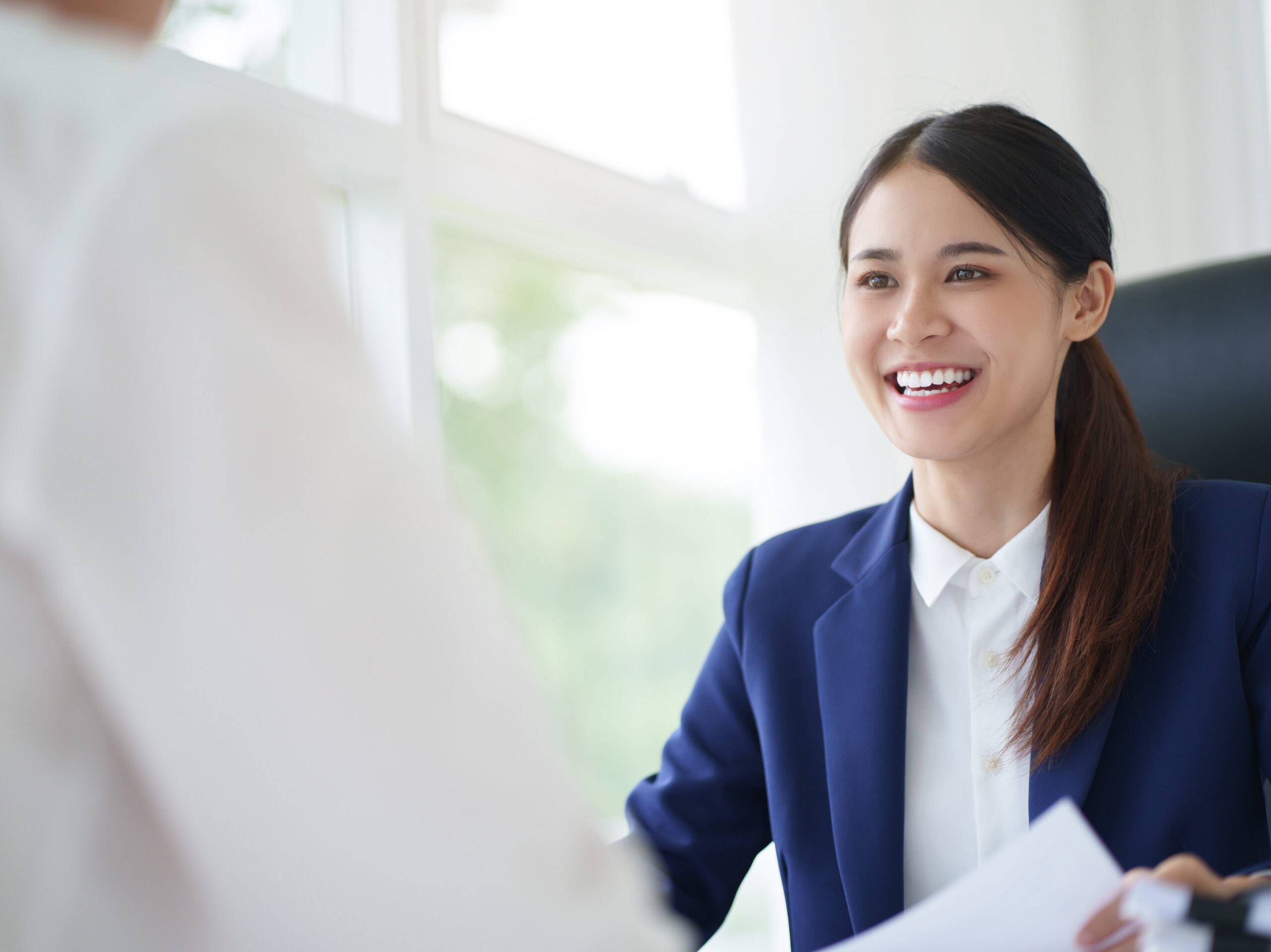 Real Estate agent representing iFinder talking to happy clients at desk in iFinder Blue suit