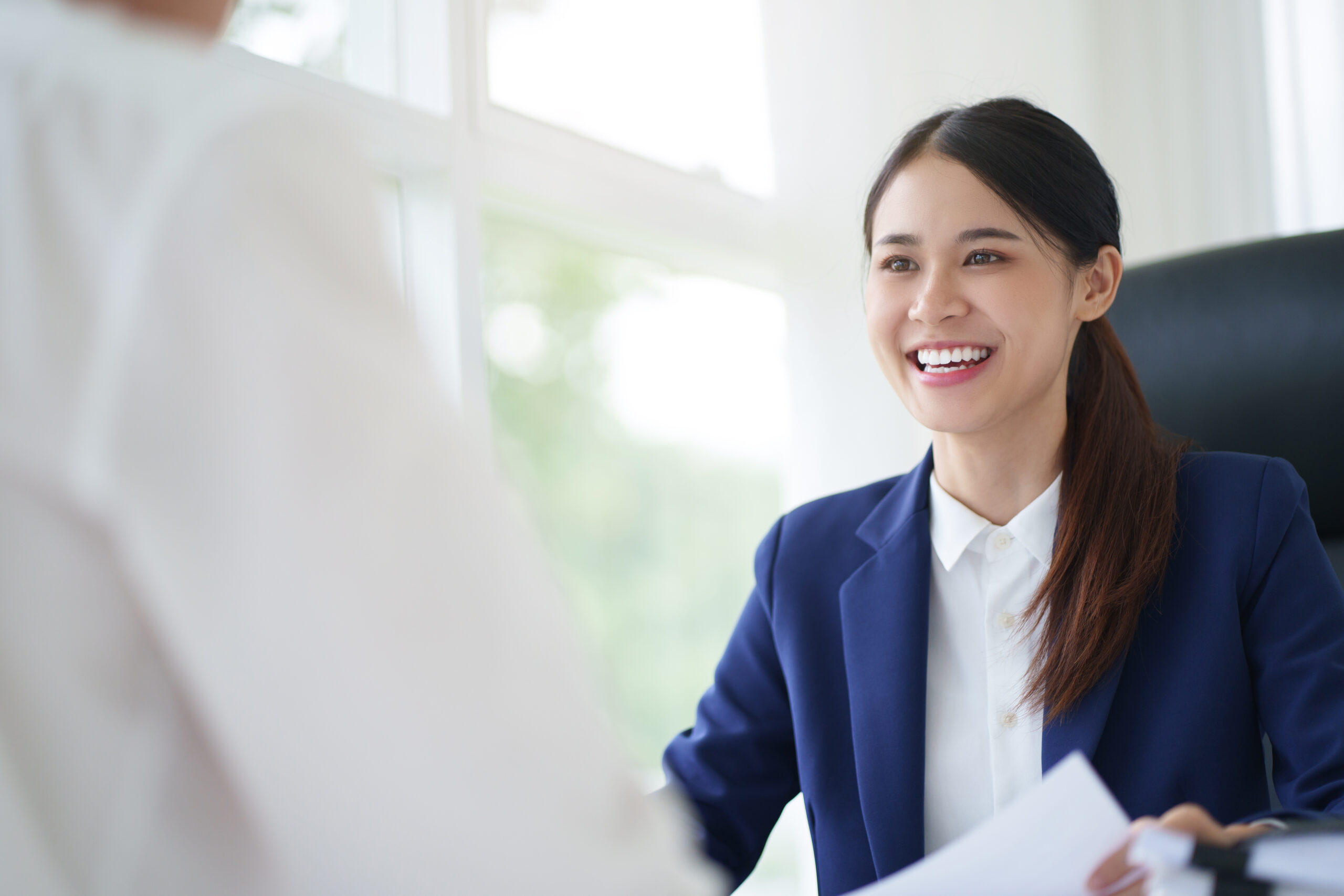 Real Estate agent representing iFinder talking to happy clients at desk in iFinder Blue suit